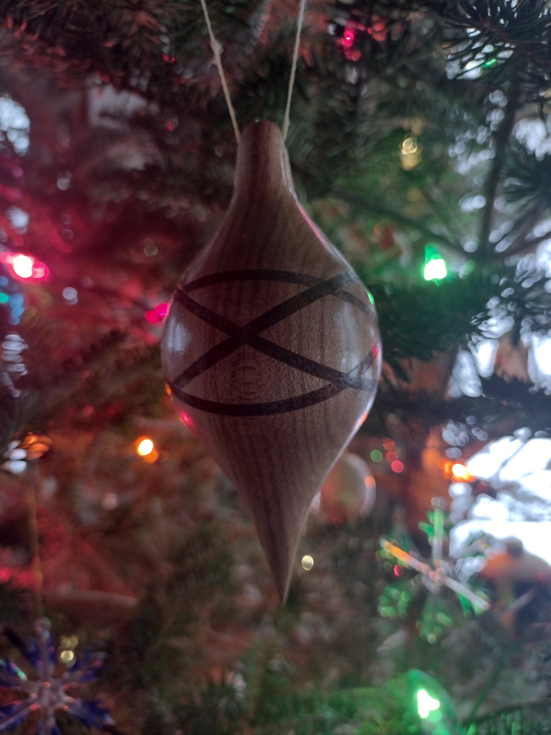 Maple-walnut hand-turned wooden ornament hanging from a Christmas tree